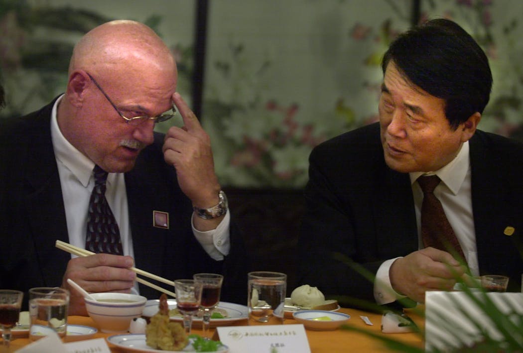 During a trade mission to China in 2002, then-Gov. Jesse Ventura shows scars from his professional wrestling days to Yu Xiaosong, chairman of the China Council for the Promotion of International Trade and China Chamber of International Commerce.