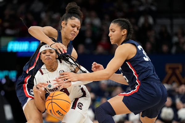 South Carolina’s Destanni Henderson is fouled as she drives between UConn’s Olivia Nelson-Ododa, right, and Azzi Fudd during the second half 
