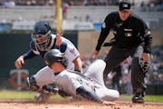 Seattle Mariners right fielder Jesse Winker (27) was tagged out at home by Minnesota Twins catcher Gary Sanchez (24) in the first inning in  Minneapol