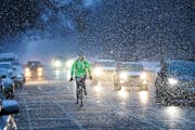 Daniel Magner rides his bike down Park Avenue towards downtown as a spring storm brought a mixed bag of precipitation to the metro, including snow Wed