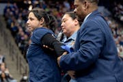 A woman, identified by an activist group as Alicia Santurio, is escorted off the court after attempting to glue her hand to the court during the Minne