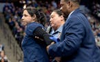 A woman, identified by an activist group as Alicia Santurio, is escorted off the court after attempting to glue her hand to the court during the Minne
