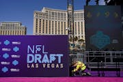 A worker helps erect a red carpet and stage in front of the Bellagio hotel-casino during setup for the NFL football draft.