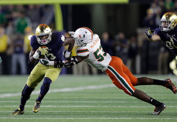 Notre Dame ‘s Josh Adams tries to evade Miami ‘s Zach McCloud.