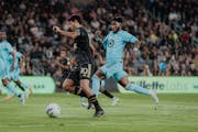 LAFC’s Carlos Vela went up the field with the ball with Minnesota United’s Oniel Fisher in pursuit Sunday night in Los Angeles.