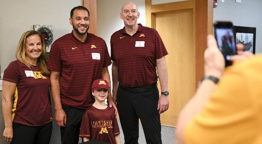 (From left) Gophers coaches Erin Chastain (soccer), Ben Johnson (men’s basketball) and Hugh McCutcheon (volleyball) stood in for a photo op with James Mueller, 6, during the Coaches Caravan on Monday.