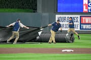 Members of the ground crew quickly pull out the tarp as the game between the Minnesota Twins and Houston Astros is delayed because of thunderstorms an