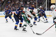 Minnesota Wild's Kevin Fiala (22) reaches for the puck next to St. Louis Blues' Niko Mikkola (77) during the third period in Game 6 of an NHL hockey S