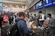 Delta ticketing agent Mohamed Abdi, right, helped a passenger check in at MSP’s Terminal 1 on Friday.