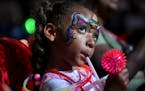 Emerson Knight, 5, watches acrobatics while taking a sip of her drink during the Royal Canadian International Circus.