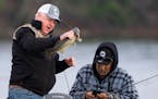 Gov. Tim Walz inspects the walleye he caught while Chairman Faron Jackson Sr. of the Leech Lake band of Ojibwe pulls up the camera on his phone during