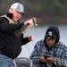 Gov. Tim Walz inspected the walleye he caught while Chairman Faron Jackson Sr. of the Leech Lake band of Ojibwe pulls up the camera on his phone durin