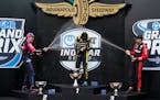 Colton Herta, center, is sprayed by Simon Pagenaud, left, of France, and Will Power, right, of Australia, after winning an IndyCar race at Indianapoli