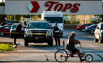 A cyclist passes the scene of a shooting at a supermarket, in Buffalo, N.Y., Sunday, May 15, 2022.