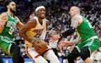 Miami Heat forward Jimmy Butler drives to the basket between Boston Celtics guard Derrick White (9) and center Daniel Theis (27) during the second hal