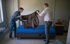 Steve Hoeppner, left, and Kevin Gronseth, volunteers at Catholic Charities, put sheets on beds in Minneapolis on Monday.