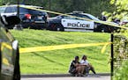 People sat on a curb at Lakeview Terrace Park near the scene of a fatal shooting on County Road 81 in Robbinsdale on Thursday. 