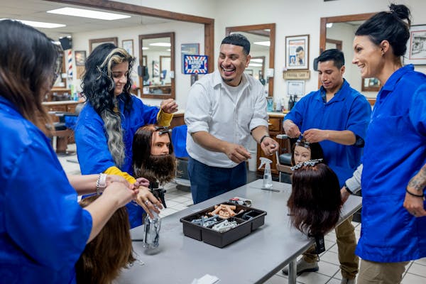 Barber Lamberto Vergara guided students on how to roll hair at the Minnesota School of Barbering in Minneapolis. Vergara purchased the school after ri