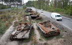 FILE - Cars pass by destroyed Russian tanks in a recent battle against Ukrainians in the village of Dmytrivka, close to Kyiv, Ukraine, May 23, 2022. T