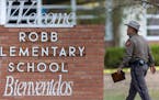 A state trooper walks past the Robb Elementary School sign in Uvalde, Texas, Tuesday, May 24, 2022, following a deadly shooting at the school. 