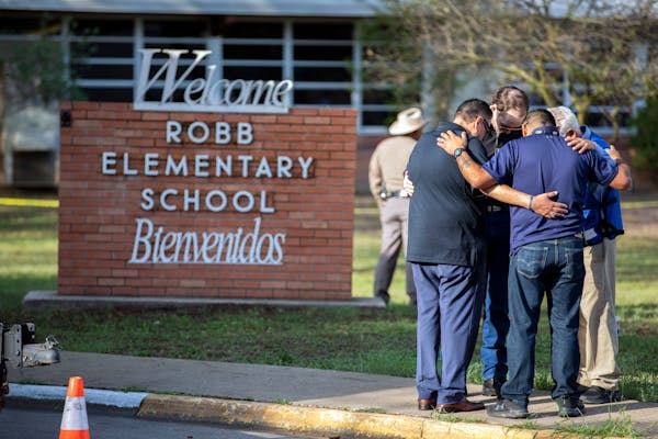 Men pray outside Robb Elementary School in Uvalde, Texas, on Wednesday morning. Harrowing details began to emerge Wednesday of the massacre inside a T