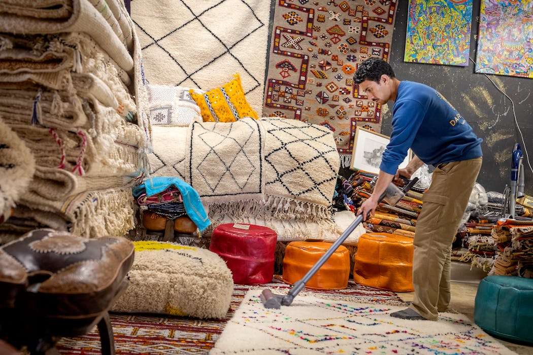 Mostafa Khchich vacuumed a rug at his Dar Medina store in the Midtown Global Market. Khchich, who sells Moroccan rugs, leather bags and other goods, says business still hasn’t returned to 2019 levels.