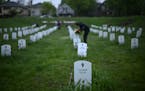 Community members lay flowers down near gravestone markers at the �Say Their Name� cemetery.