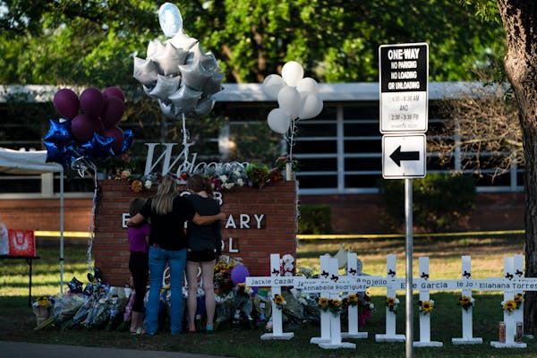 A family pays their respects next to crosses bearing the names of Tuesday’s shooting victims at Robb Elementary School in Uvalde, Texas, Thursday. 