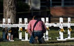 Pastor Daniel Myers kneels in front of crosses bearing the names of Tuesday’s shooting victims while praying for them at Robb Elementary School in U