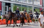 Mounted Houston police officers patrol the street between the George R. Brown Convention Center and Discovery Green Park, where protesters began gathe