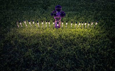 Lights illuminated a cross made of flowers at a memorial site in the town square for the victims killed in this week’s elementary school shooting in