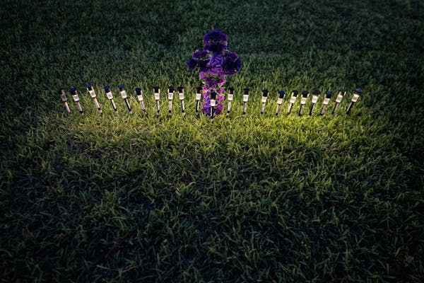 Lights illuminated a cross made of flowers at a memorial site in the town square for the victims killed in this week’s elementary school shooting in
