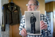 Hollis Schwartz, 97, holds up a photo of when he served in the Army during WWII at his home in Chaska May 19. 