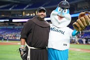 The Rev. Roberto “Tito” Serrano poses with the Miami Marlins mascot after throwing out the first pitch.