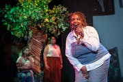 Queen Drea sings as actors Kyra Richardson and Aimee K. Bryant perform in a scene of “Spittin’ Seeds” at Penumbra Theatre.