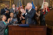 Gov. Tim Walz celebrates after signing a bill to direct payments to frontline workers and replenish the unemployment insurance trust fund.