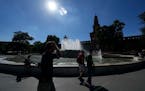 People walk next to the public fountain in front of the Sforzesco Castle, in Milan, Italy, Saturday, June 25, 2022. The mayor of Milan signed an ordin