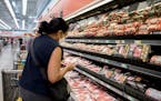 Mai Fee compares the prices of different meats at a grocery store in Vancouver, Wash., on June 14, 2022.