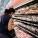 A woman compares the prices of different meats at a grocery store in Vancouver, Wash., on June 14.