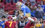 UCLA quarterback Dorian Thompson-Robinson hurdles high over USC safety Chase Williams, left, and cornerback Isaac Taylor-Stuart when the teams played 