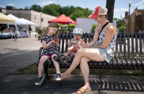 Jenni Loebel offered fresh strawberries to her kids Brynn, 4, and JJ, 2 at the Lakeville Farmer’s Market, Market Plaza.