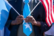 An attendee wore a Somali flag tie while holding Somali and American flags during the Somali Independence Day festival on July 2 on Lake Street in Min