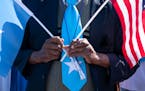 An attendee wore a Somali flag tie while holding Somali and American flags during the Somali Independence Day festival on July 2 on Lake Street in Min