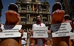 People dressing as dinosaurs and white and red San Fermin’s colors protest in front of the City Hall against animal cruelty before the start of the 