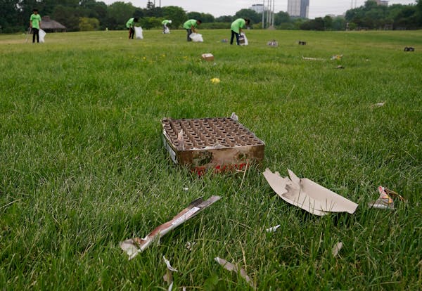 Workers from Teen Teamworks pick up litter, including remnants of exploded fireworks, on Tuesday at Boom Island Park in Minneapolis. Gunfire at the pa