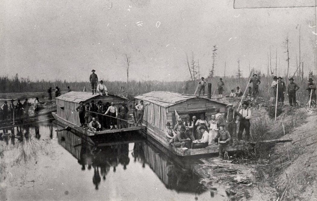Lumberjacks posed for a photograph alongside wanigans floating on the Mississippi River in the 1880s.