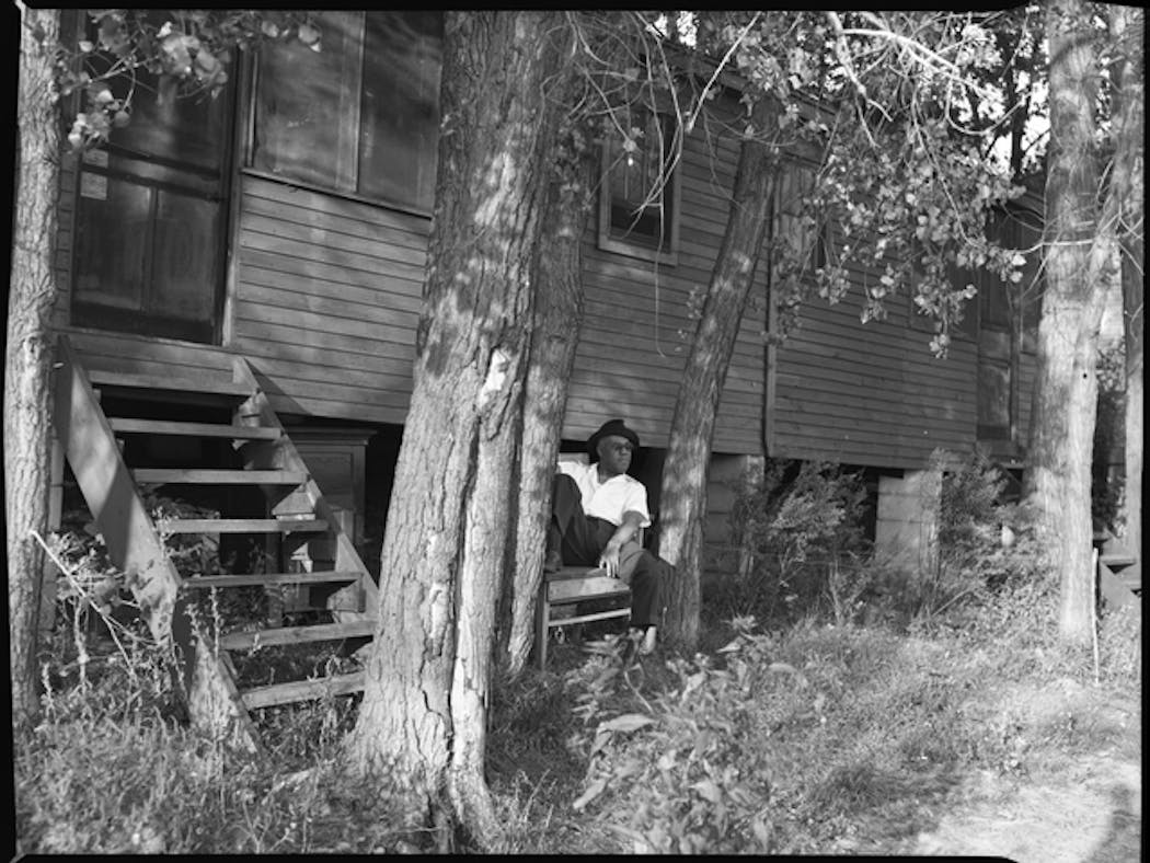 A man relaxes outside a cabin along Lake Adney in this circa 1955 photo.