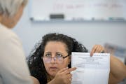 Election judge Dr. Hayet Abbassi assists voters at the Minneapolis early voting center on Wednesday, Aug. 3.