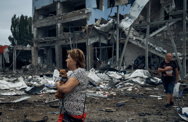 A woman holds a dog in the aftermath of the Russian shelling in Mykolaiv, Ukraine, Wednesday, Aug. 3, 2022.
