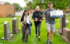 Therese Phan, 17, Iris Stone, 19, and Murray McCartan left to right, walk with grave markers Saturday, August 6, 2022 at Church of the Assumption of t